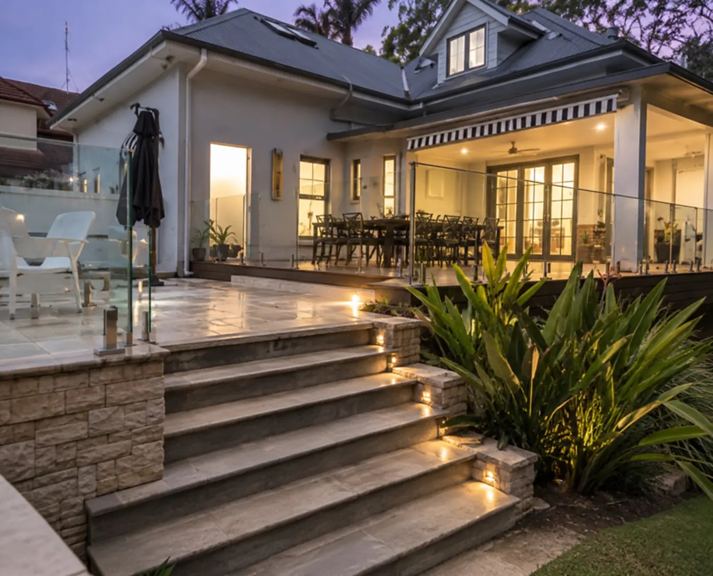 Wide outdoor steps leading up to a lit alfresco deck at a Wollongong home