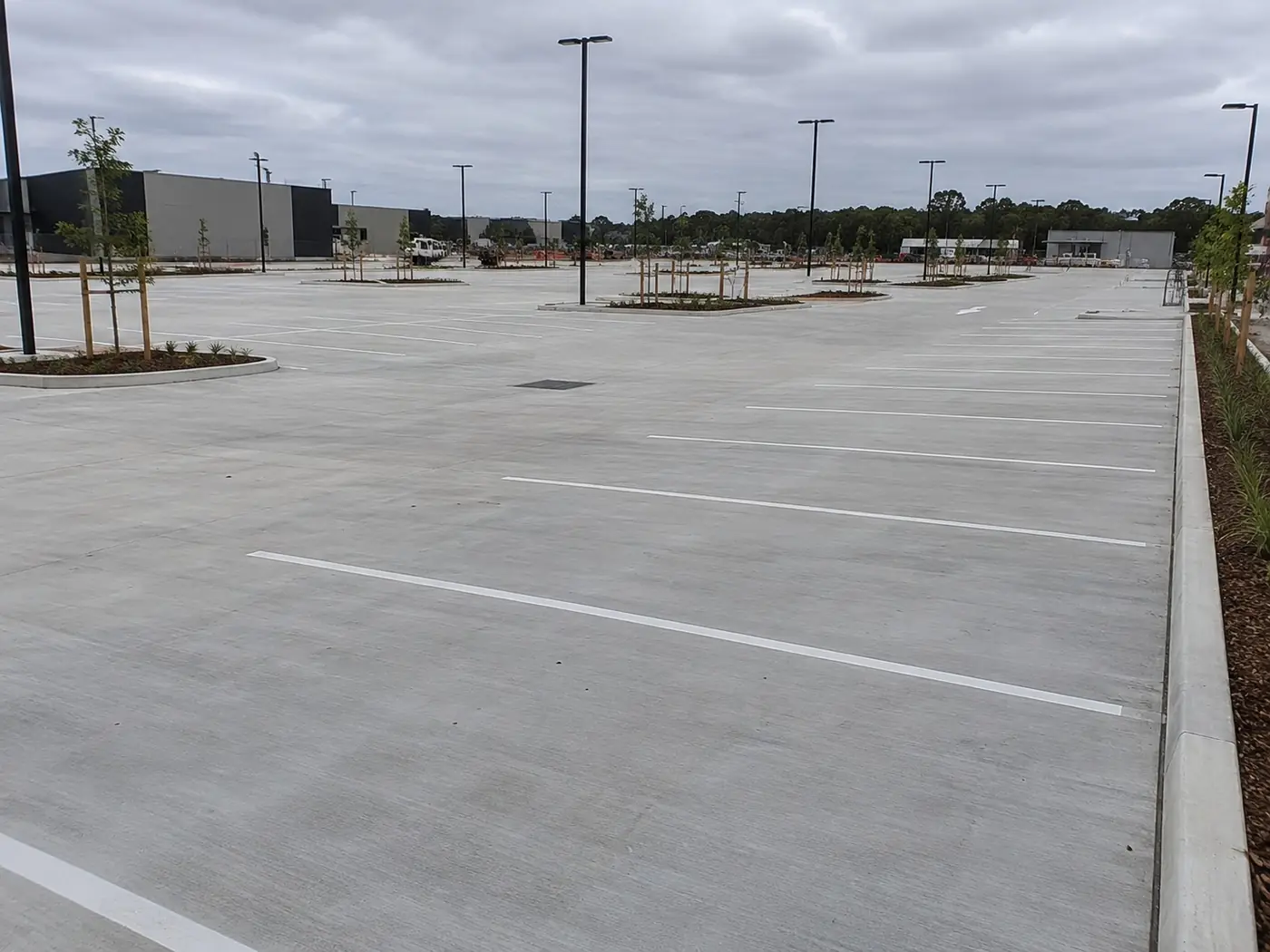 Wide concrete car park with marked bays and drainage pits