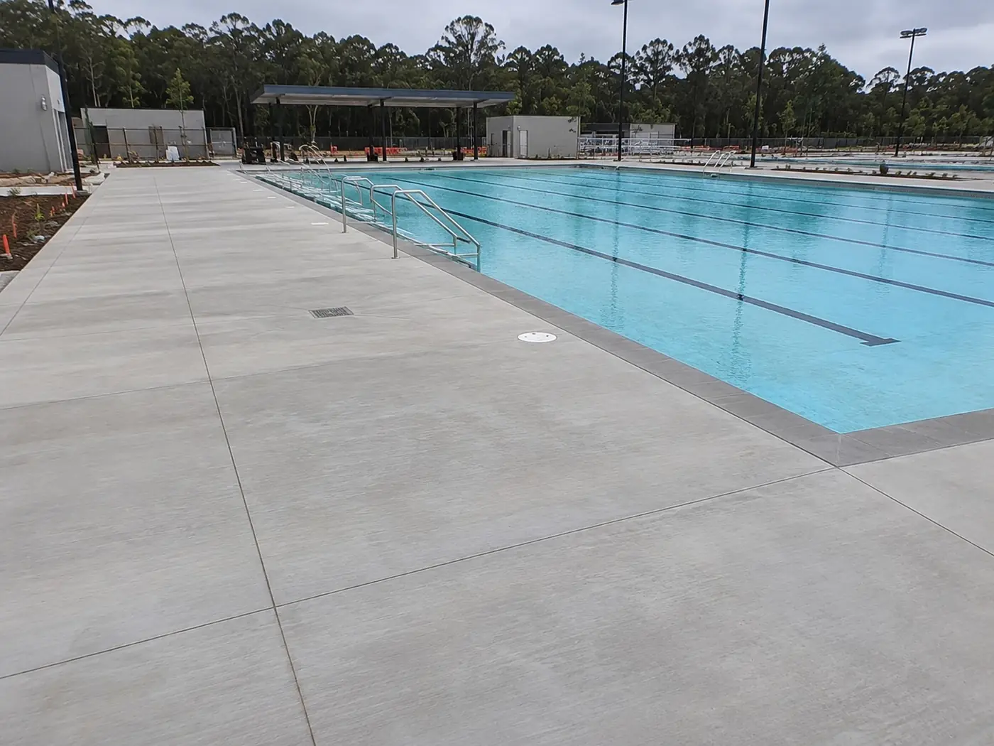 Broad concrete pool surround with drainage along an outdoor lap pool