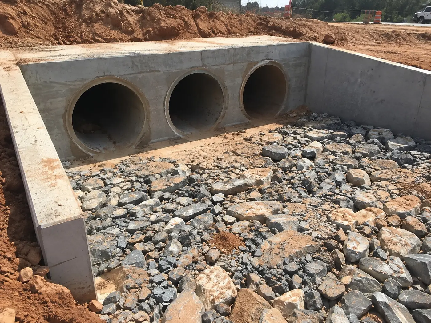 Triple-pipe concrete stormwater headwall with wingwalls and rock apron